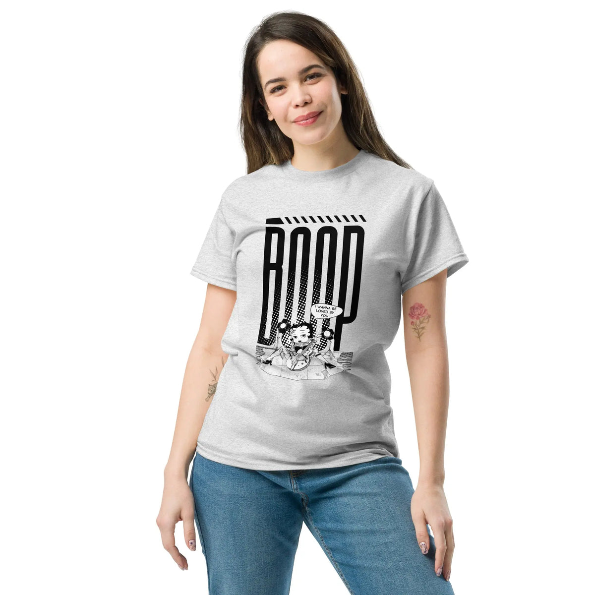 Woman wearing an ash graphic tee with a Betty Boop-inspired rock star design, styled with blue denim jeans