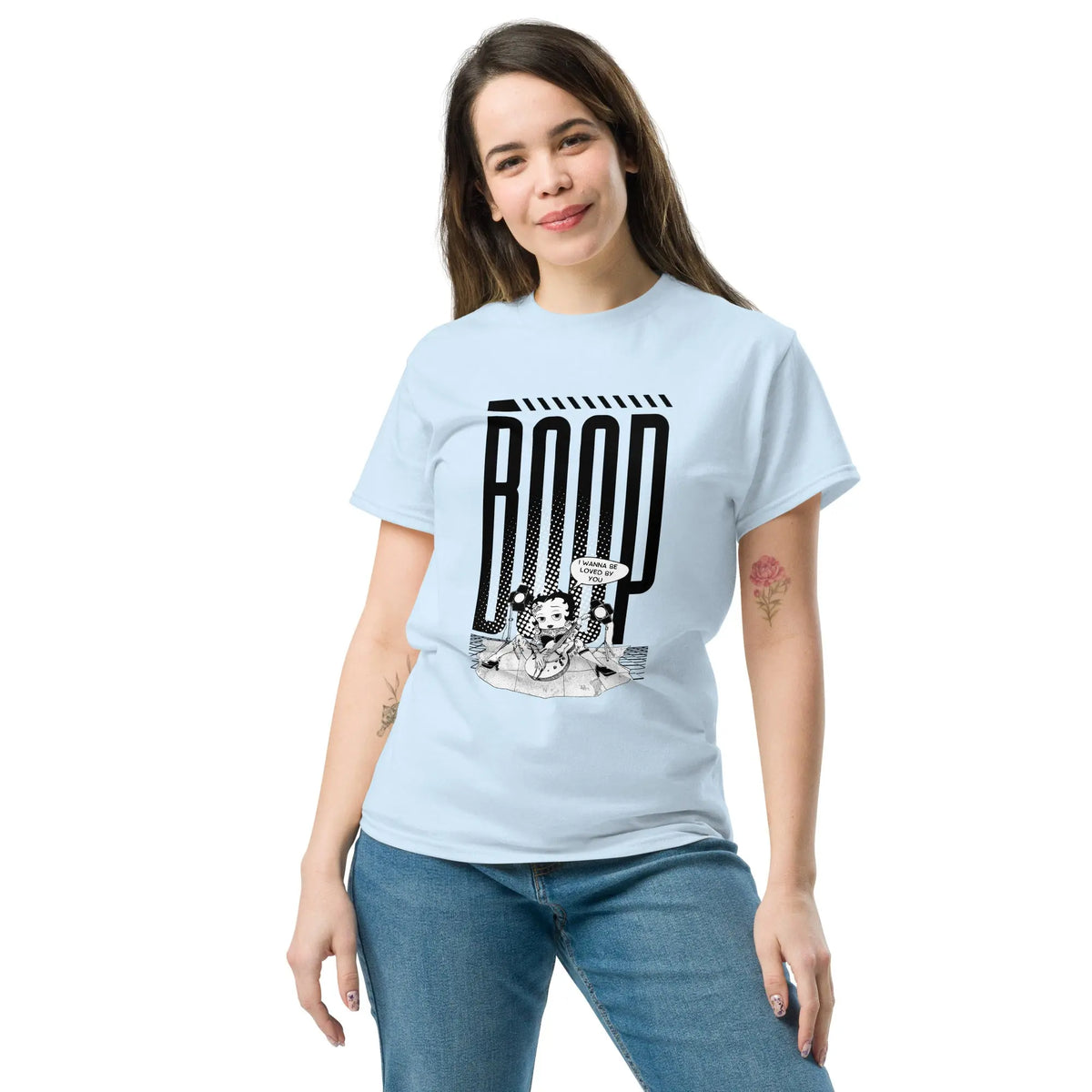 Woman wearing a light blue graphic tee with a Betty Boop-inspired rock star design, styled with blue denim jeans