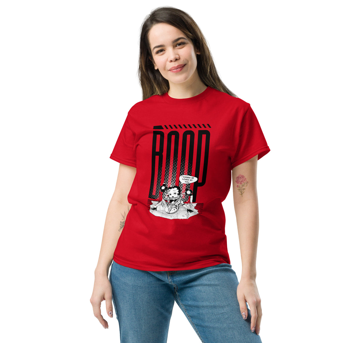 Woman wearing a red graphic tee with a Betty Boop-inspired rock star design, styled with blue denim jeans