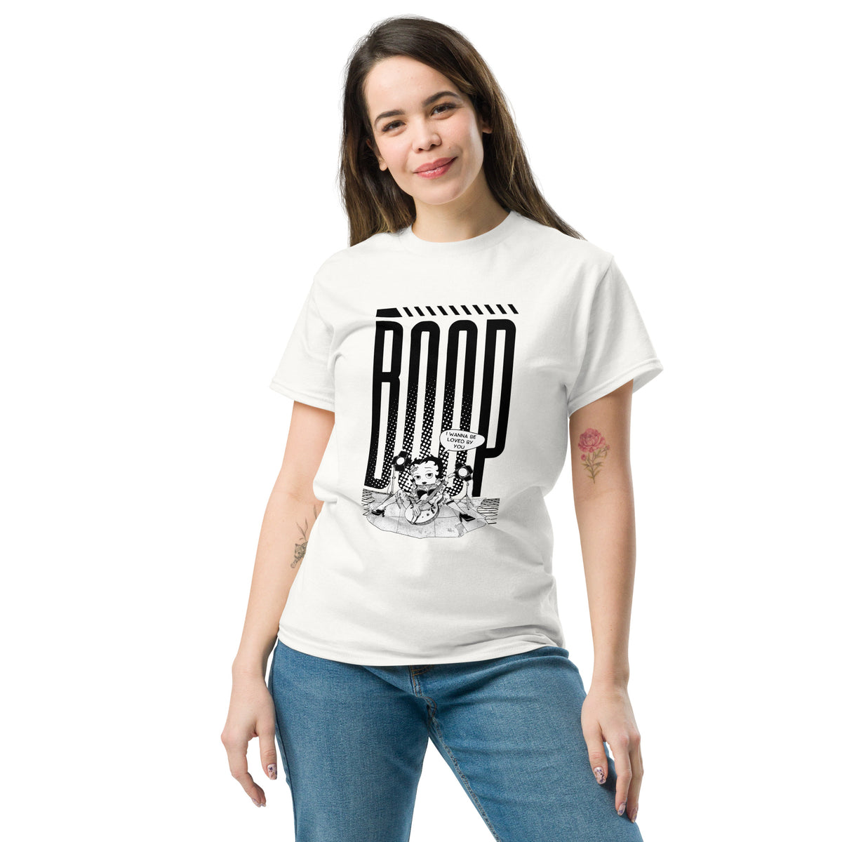 Woman wearing a white graphic tee with a Betty Boop-inspired rock star design, styled with blue denim jeans