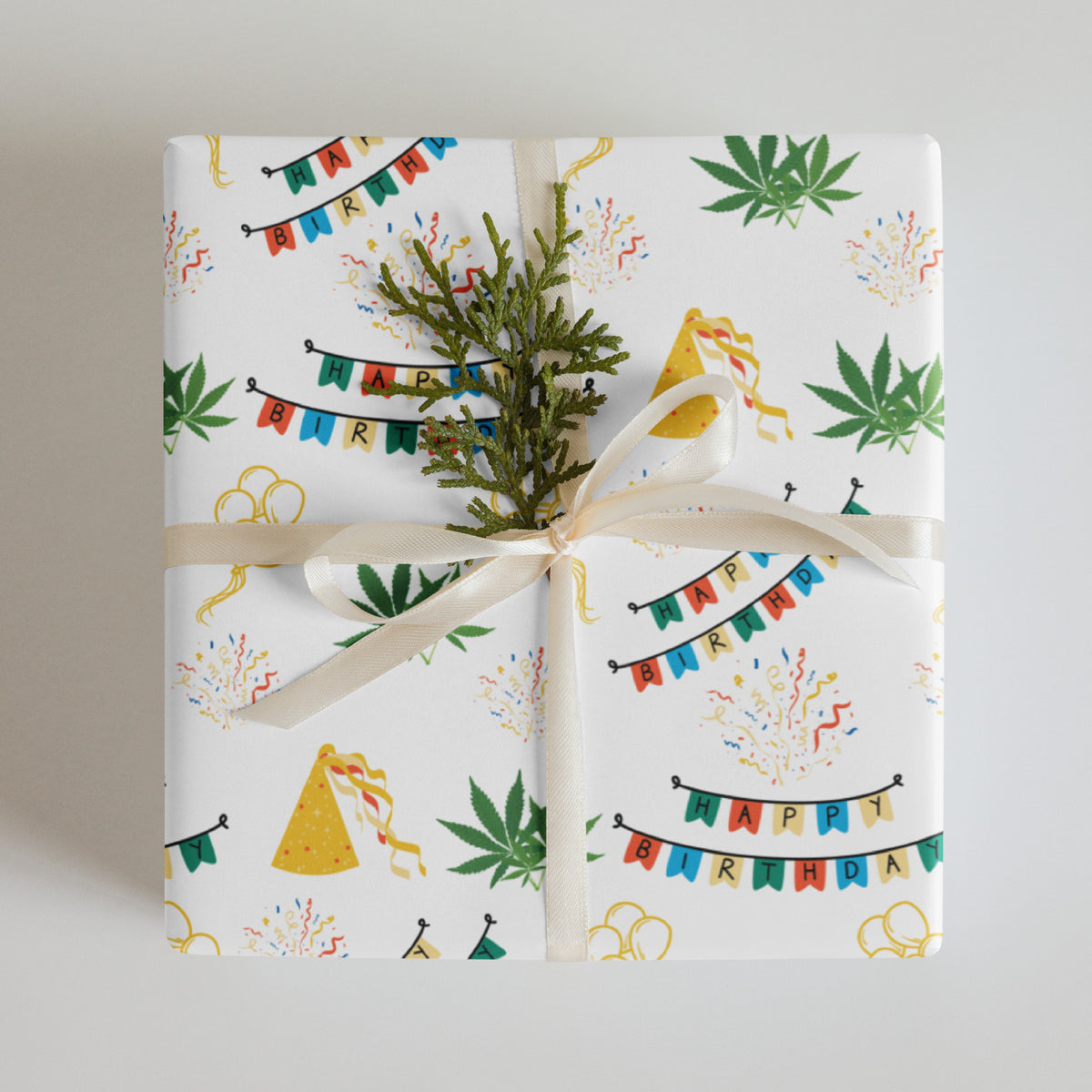 White cannabis-themed birthday wrapping paper with colorful banners, party hats, confetti, balloons, and green leaves