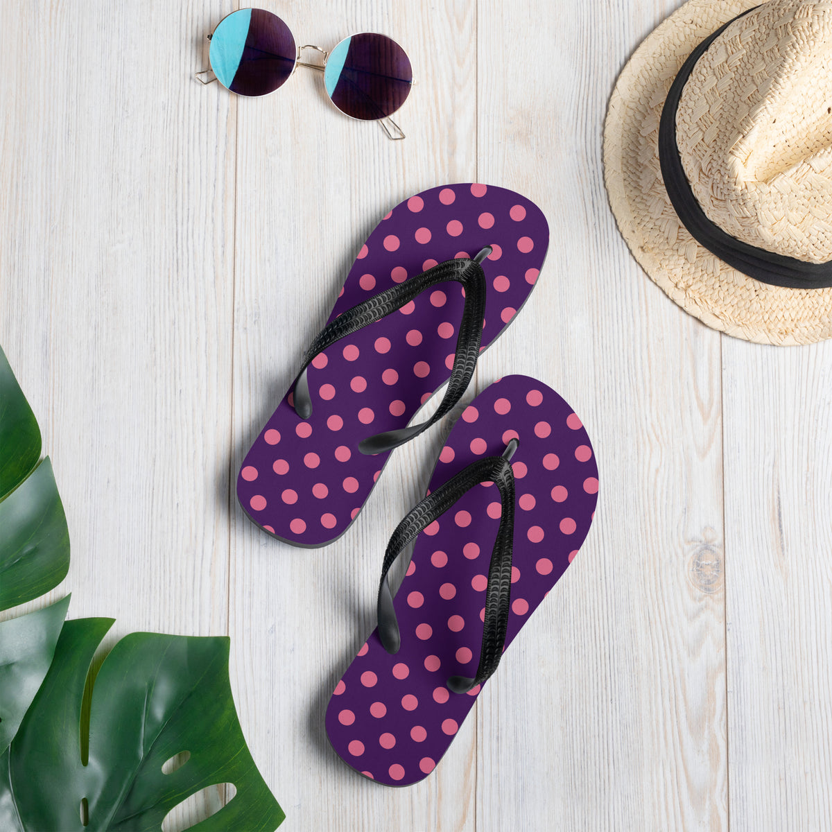 Pink polka dot flip-flops on a purple background with black straps