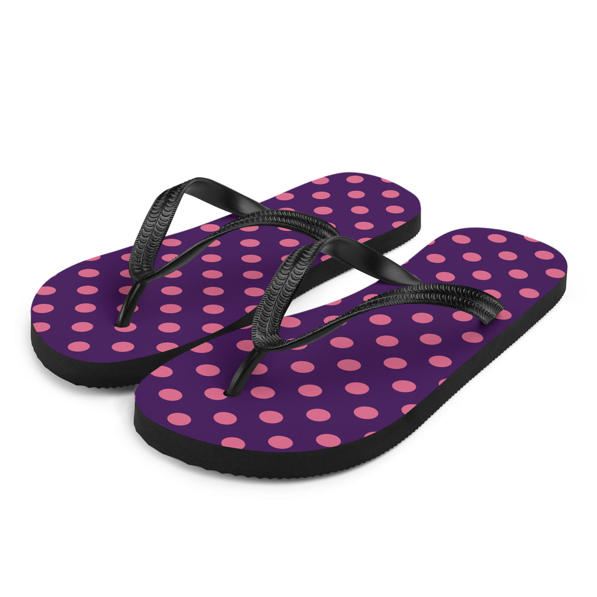 Pink polka dot flip-flops on a purple background with black straps