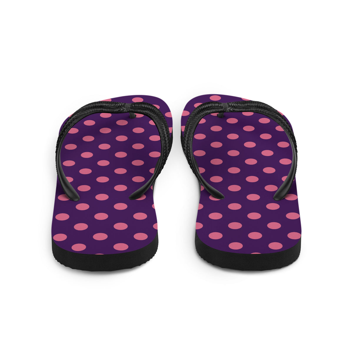 Pink polka dot flip-flops on a purple background with black straps