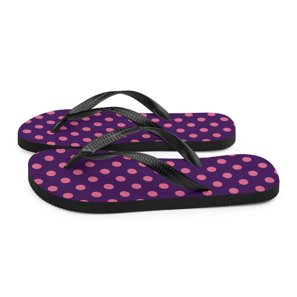Pink polka dot flip-flops on a purple background with black straps