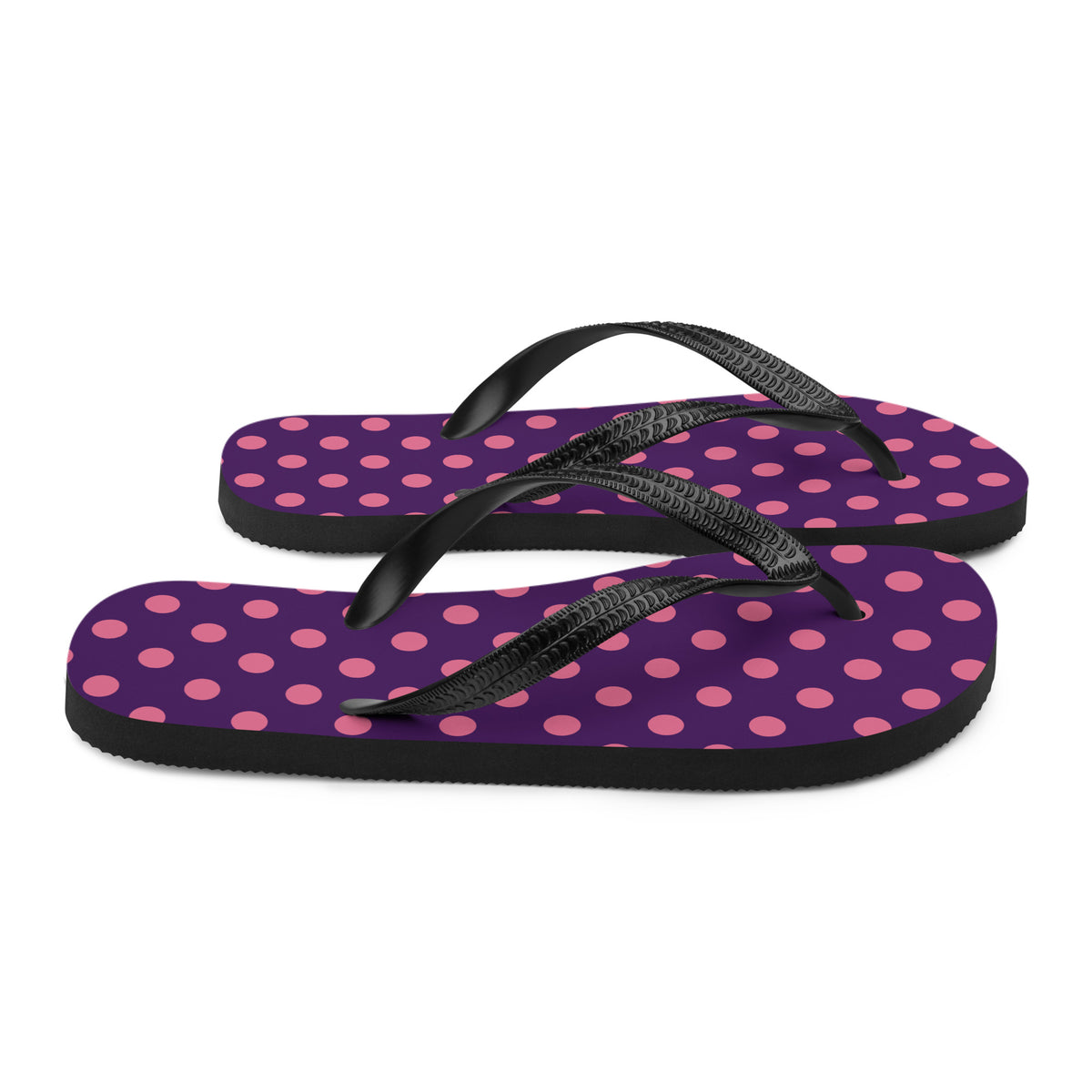 Pink polka dot flip-flops on a purple background with black straps