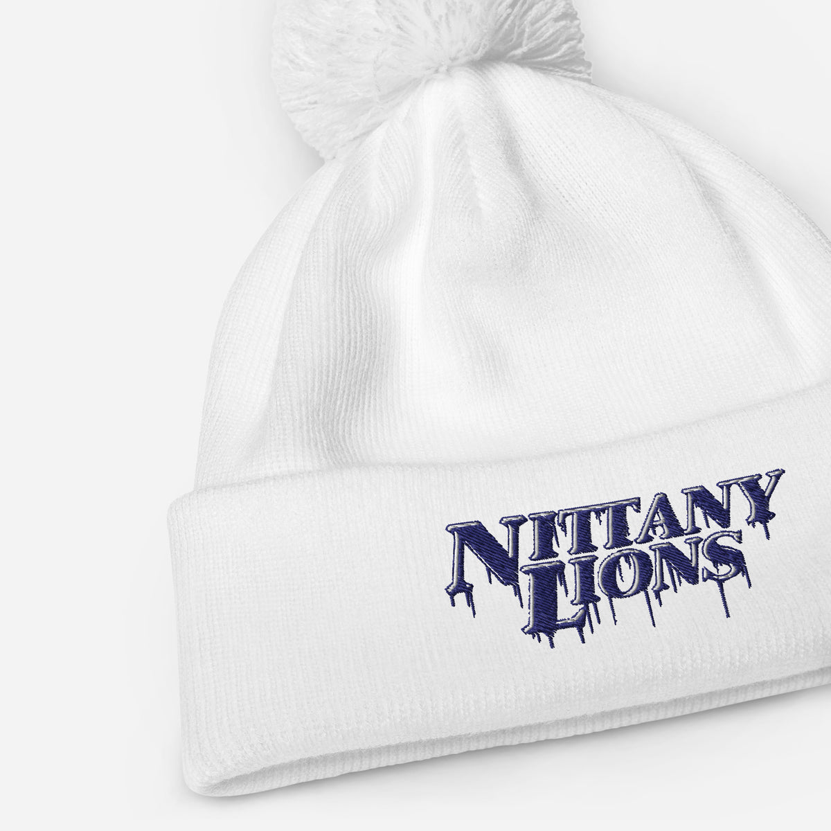 White pom pom beanie with bold embroidered Nittany Lions lettering on the front cuff