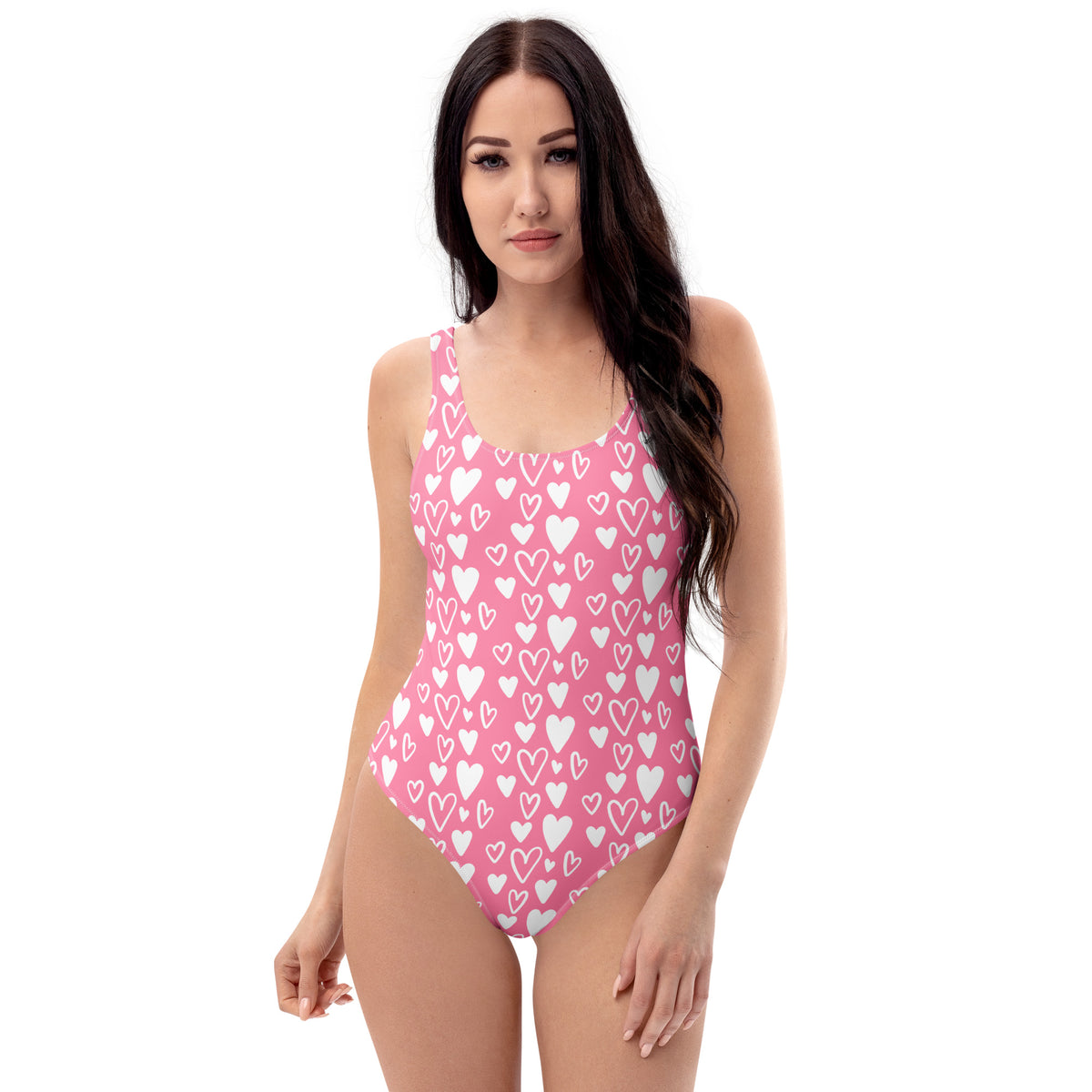 A model wearing a Pink one-piece swimsuit covered in solid and outlined white hearts with a scoop neckline and cheeky fit