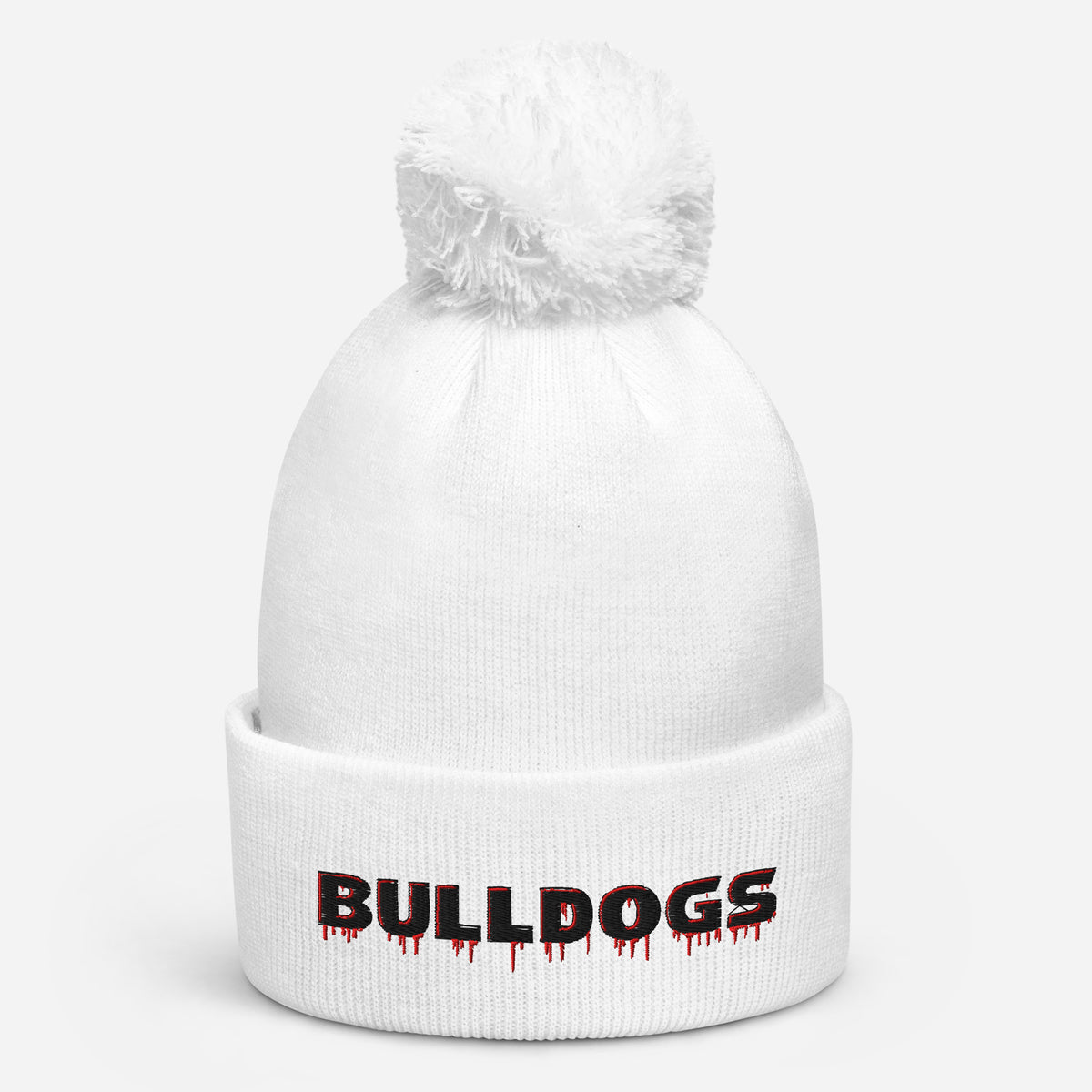 A white Bulldogs-inspired pom pom beanie featuring bold red-and-black embroidered lettering, soft-touch acrylic, a double-layer knit, and classic cuffed styling.
