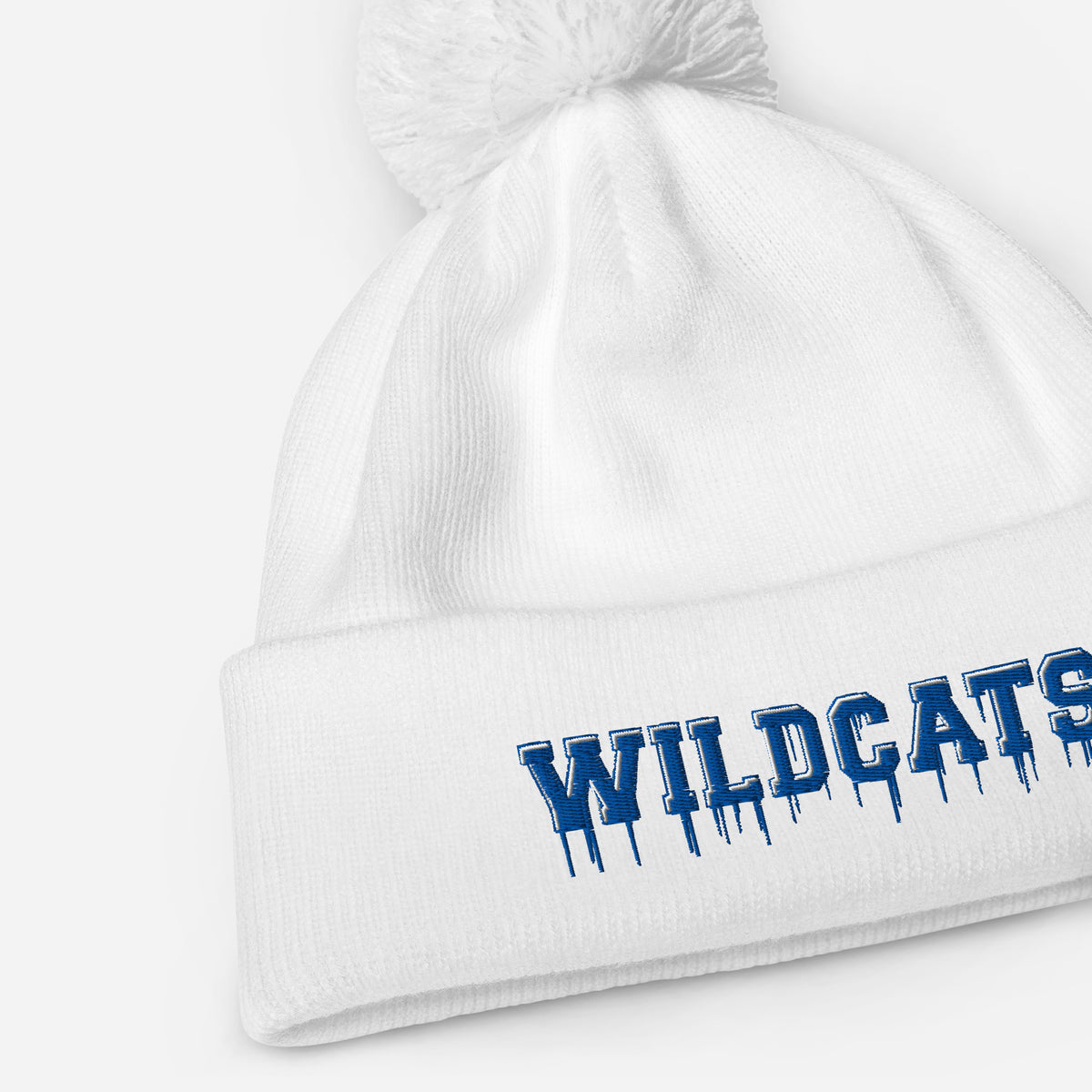 White pom pom beanie with bold blue embroidered Wildcats lettering on the front cuff