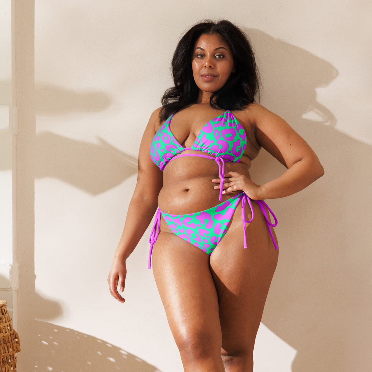 Model wearing pink and aqua cheetah print two-piece string bikini with triangle top and tie-side bottoms