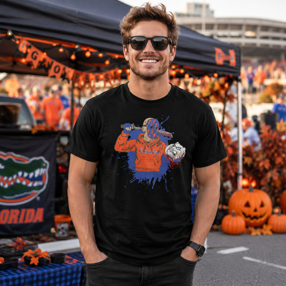 Man wearing a black Florida Halloween rivalry game day T-shirt with a slasher-style football graphic at a festive tailgate scene with pumpkins, orange lights, fall decor, and game day decorations.