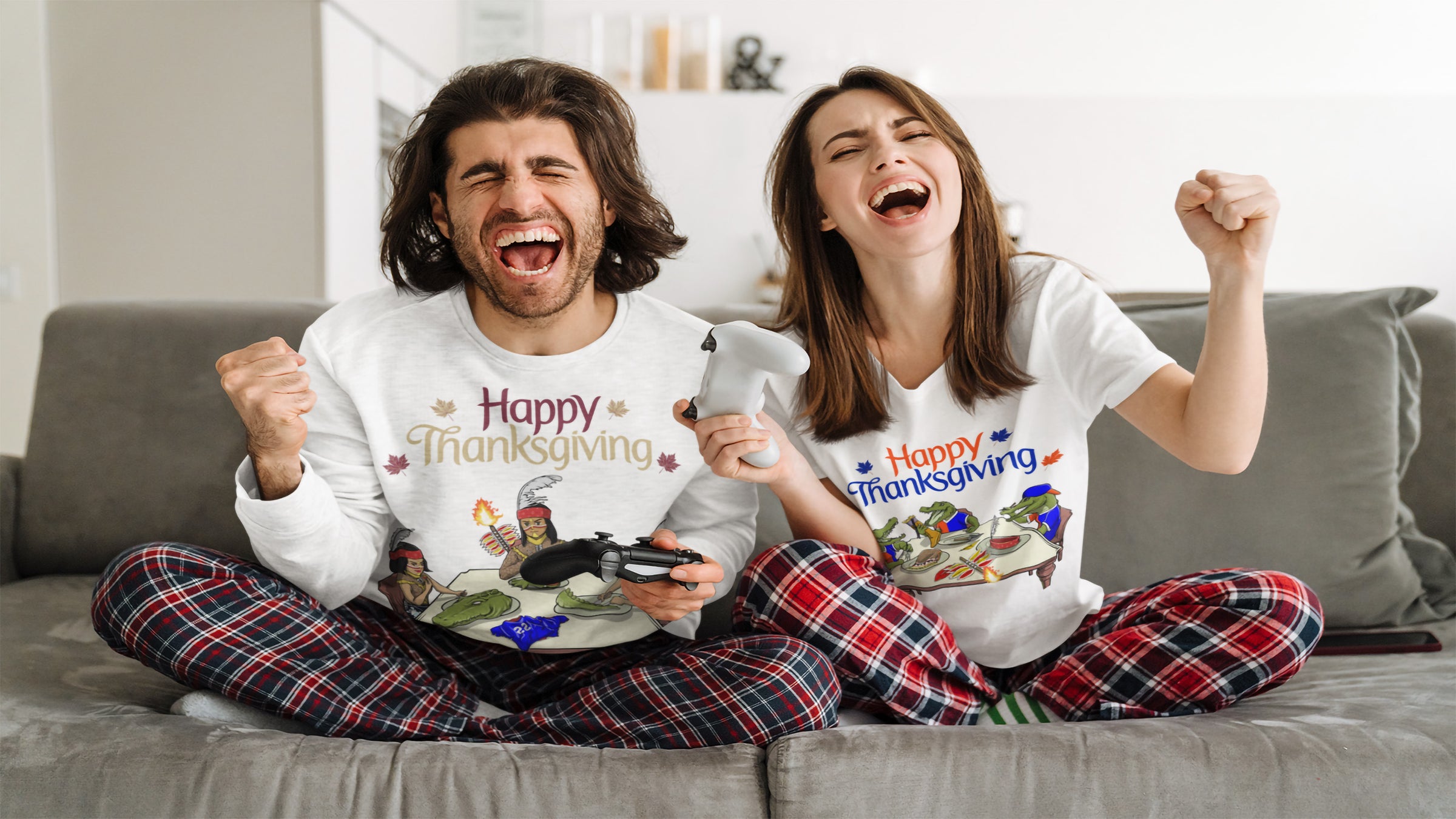 A couple wearing Happy Thanksgiving rivalry shirts celebrates excitedly on a couch while holding game controllers, showing holiday and game-day team spirit